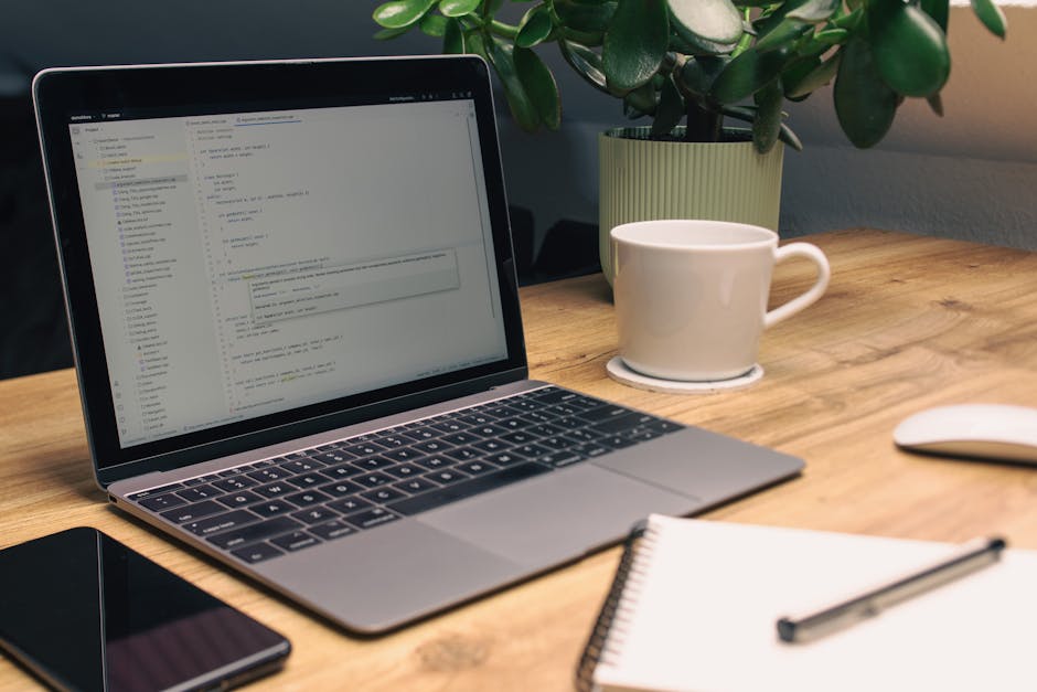 A modern workspace with a laptop, notepad, and coffee cup.