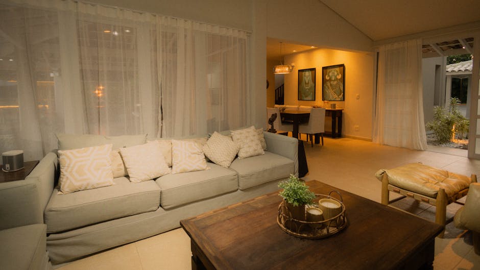 A cozy living room with a coffee table and laptop, softly lit.