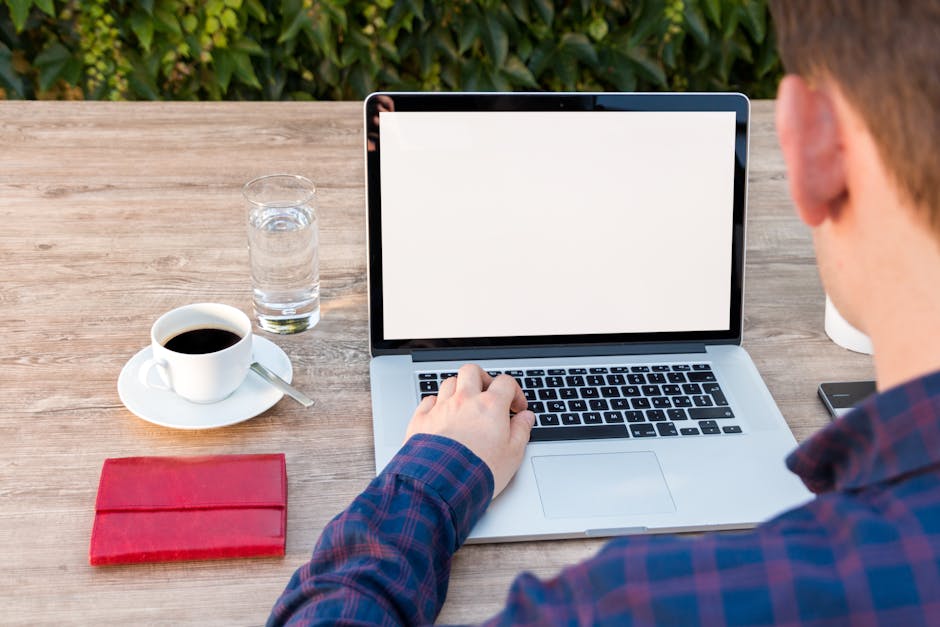 A modern office desk with a laptop, coffee cup, and notepad under soft lighting.
