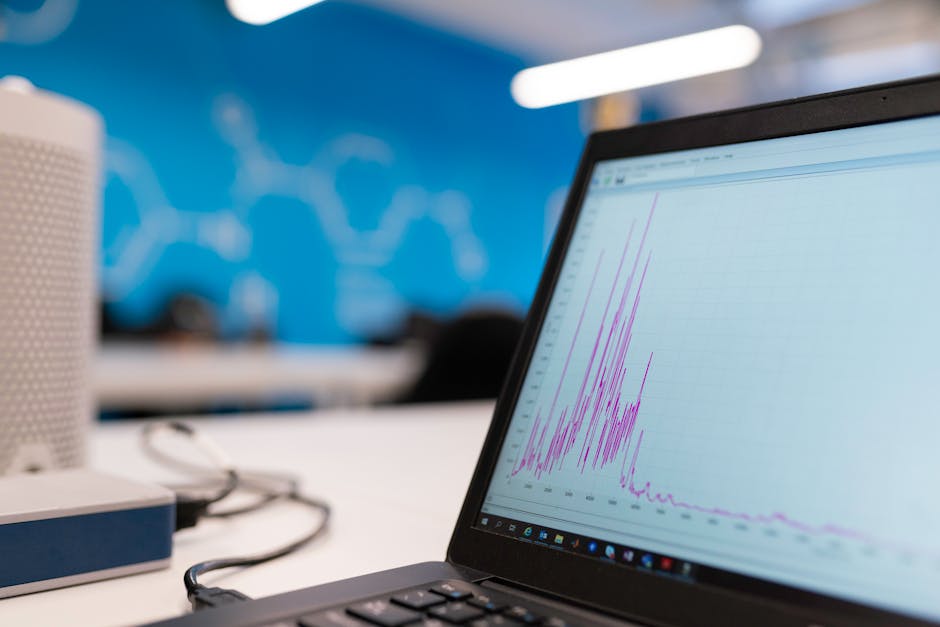 A modern workspace featuring a laptop and analytical graphs on the screen.