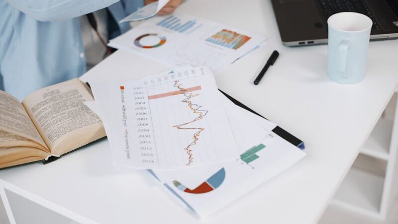 A modern workspace with a laptop and financial graphs on a desk