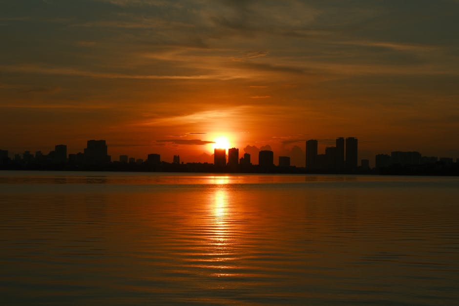 Philippine city skyline at dusk with glowing lights and calm waters.