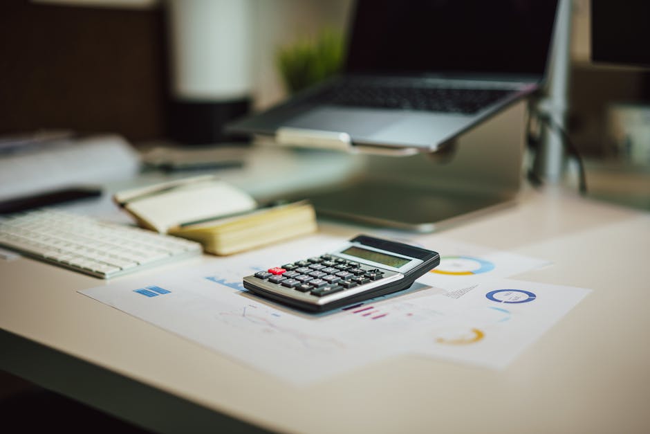 A modern workspace with a laptop and financial tools on a desk.