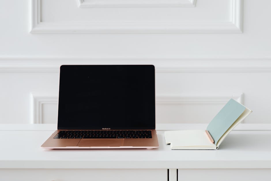 A clean desk with a laptop and open notebook in soft light.