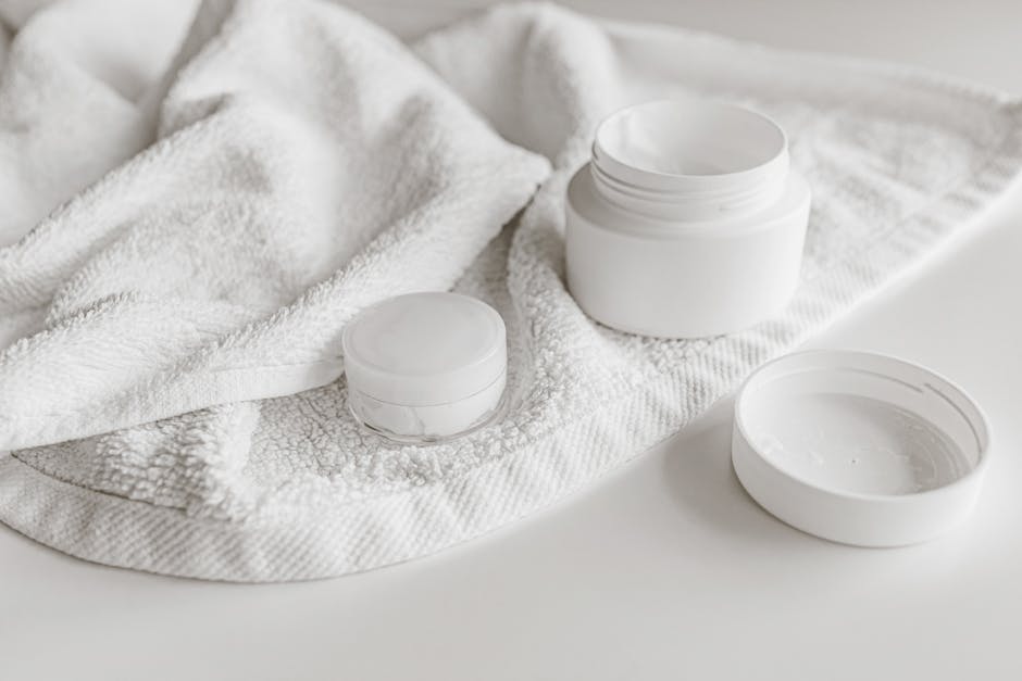 A soft-focus bathroom shelf with skincare products and greenery.