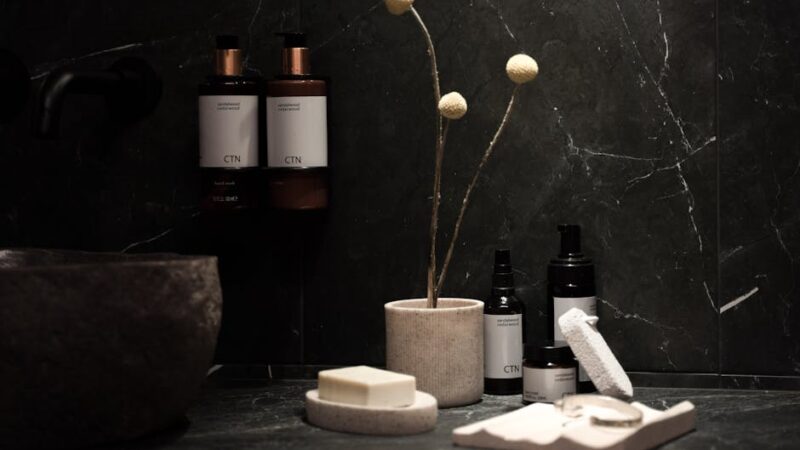 Elegant skincare products on a marble countertop with plants and tea.