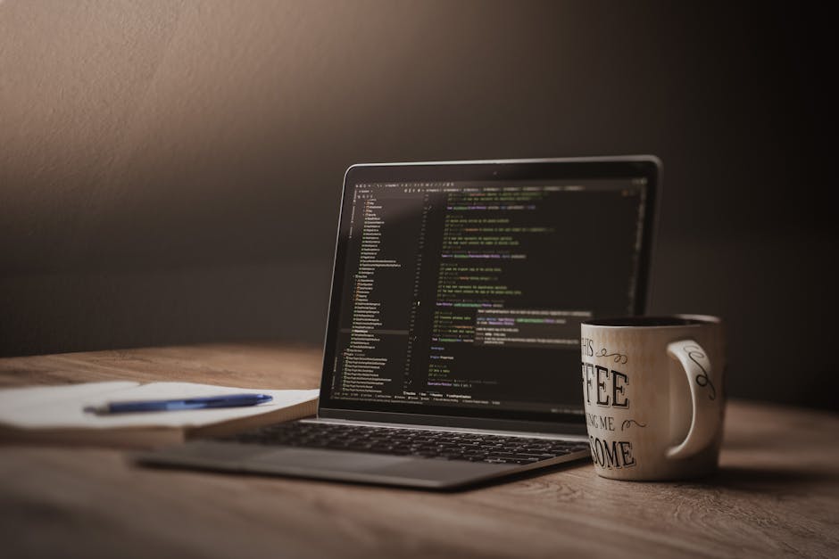 A workspace with a laptop, notebooks, and a coffee cup in soft light.
