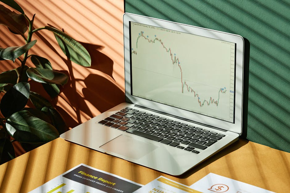 A trading desk with a laptop, charts, and greenery in soft lighting.