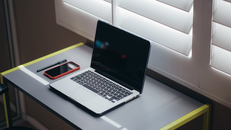 A modern workspace with a laptop, tablet, and smartphone on a desk.