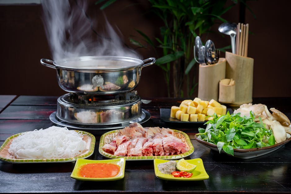 A steaming hotpot with colorful ingredients on a wooden table.