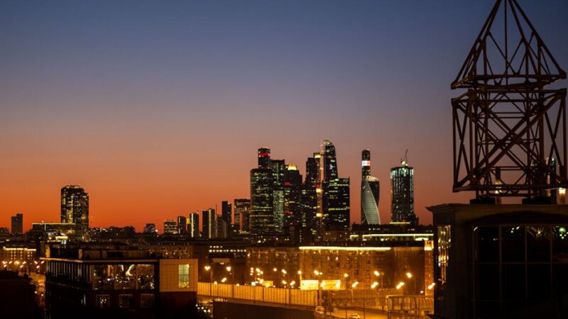 A futuristic city skyline illuminated by vibrant lights at dusk.