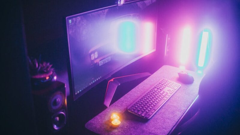 A colorful gaming setup with a chair, keyboard, and illuminated screen.