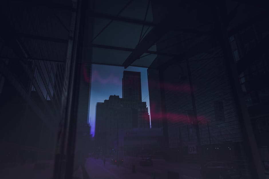 City skyline at dusk with vibrant lights reflecting on glass buildings.