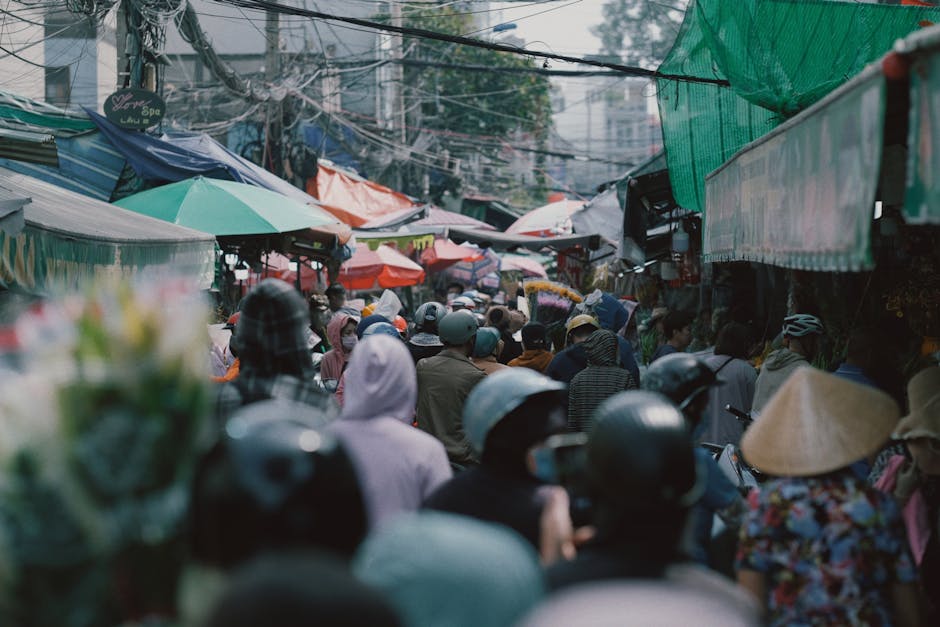 A busy Asian street market with colorful stalls and shoppers.