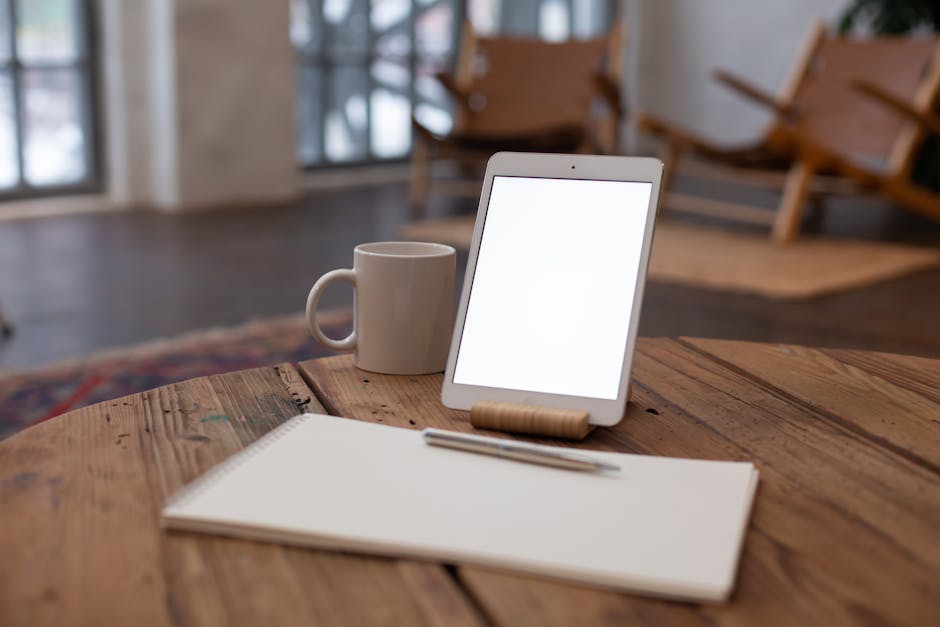 A modern workspace with a laptop, notepad, and tablet on a desk.