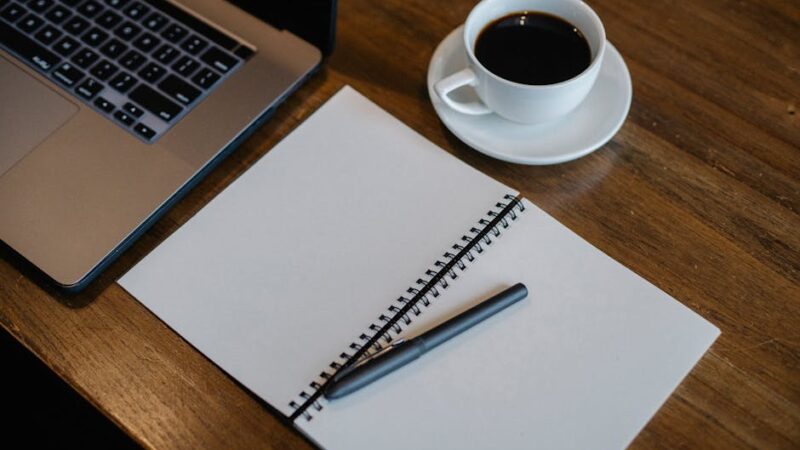 A cozy modern workspace with a laptop and notepad on a desk.