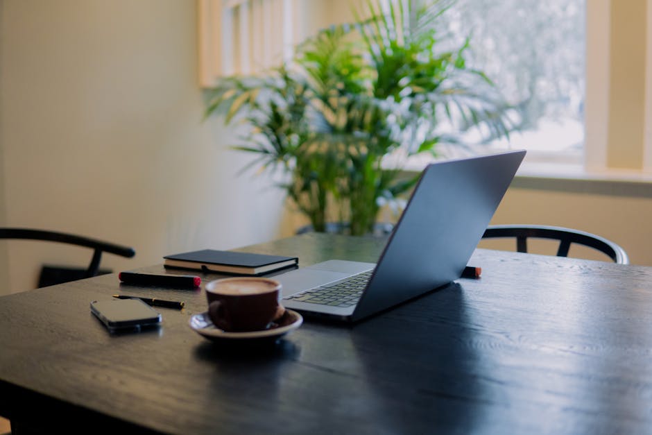 A bright workspace with a laptop and colorful stationery in a coffee shop.