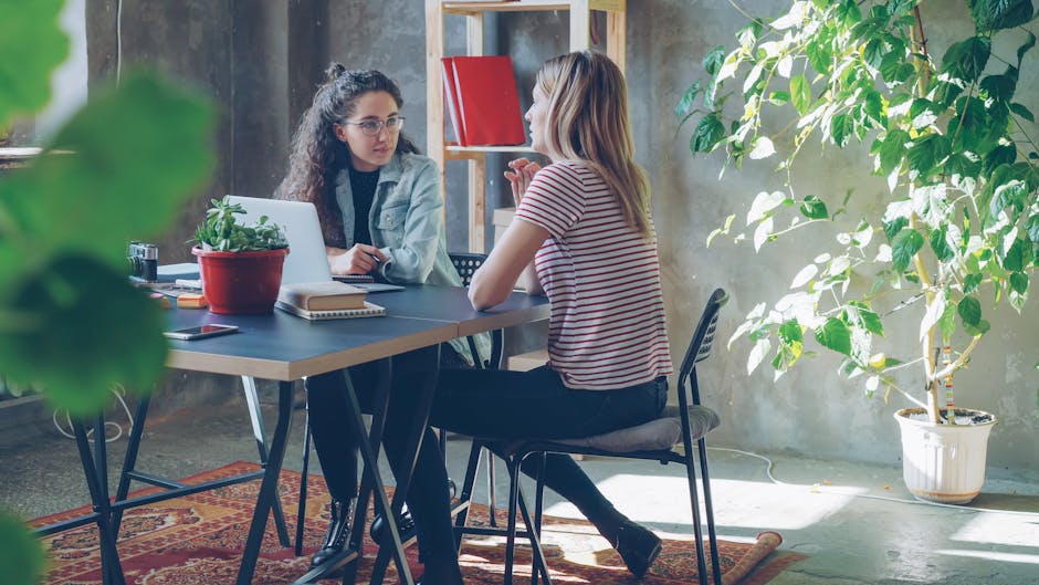 A bright workspace with a laptop and green plants in soft light.