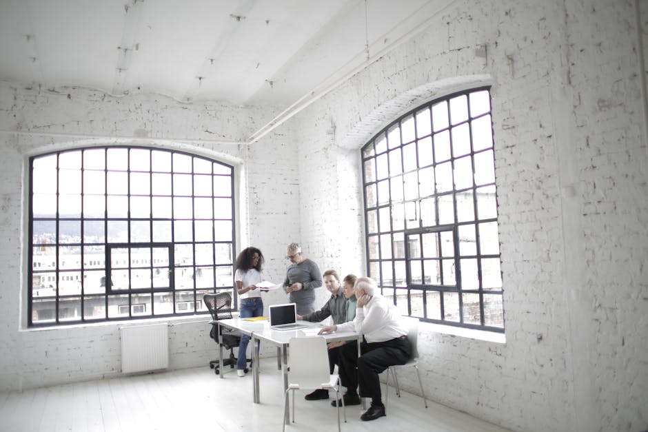 A modern office with diverse professionals collaborating around a table.