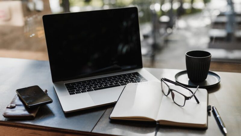 A modern workspace with a desk, laptop, and coffee cup in soft light.
